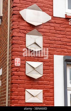 Folding a metal envelope on a red brick wall Stock Photo