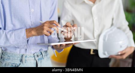 Sustainable Engineering Collaboration. Two engineers discussing project on tablet with safety gear. Stock Photo
