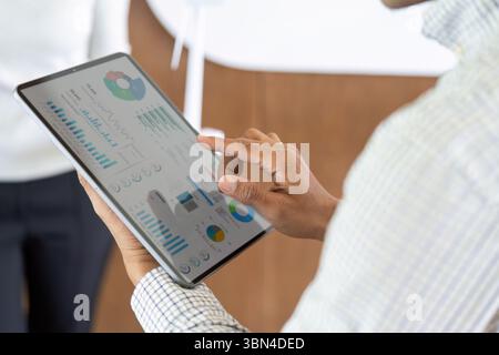 Data Visualization and Insights. Professional analyzing business metrics on tablet in modern office. Stock Photo