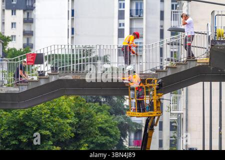 Workers on a footbridge in front of a building Stock Photo