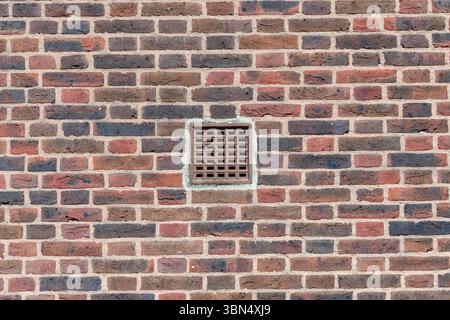 Red brick wall with a ventilation grid Stock Photo