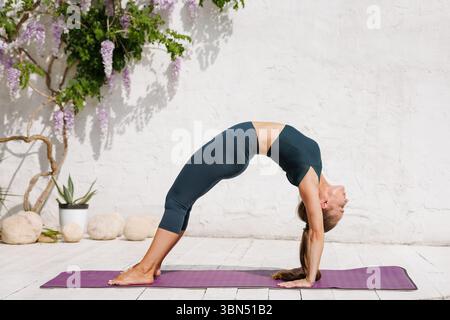 Woman practicing advanced yoga bridge pose outdoors for flexibility strength and healthy spine wellness Stock Photo