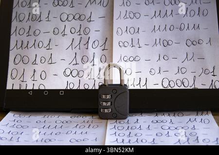close-up of a tablet screen displaying handwritten binary code, with a combination padlock resting in front, symbolizing data security Stock Photo