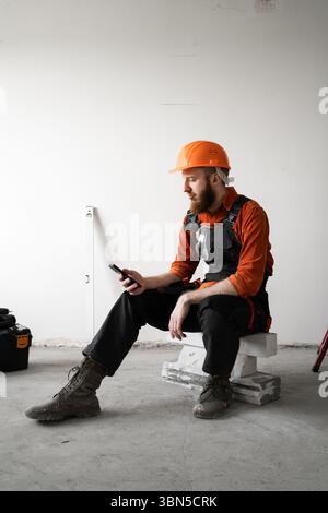 Builder with phone. construction worker texting, chatting and reading info for building development. mobile app at property. Copy space Stock Photo