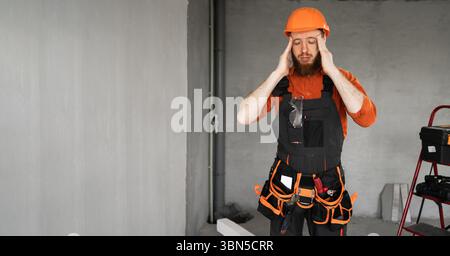 headache concept. stressed male builder or civil engineer suffering from headache and migraine, feeling unwell, while making house repair. Copy space Stock Photo