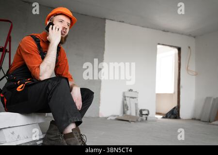 Construction worker or builder calling on smartphone. profession, technology, construction and building concept Stock Photo