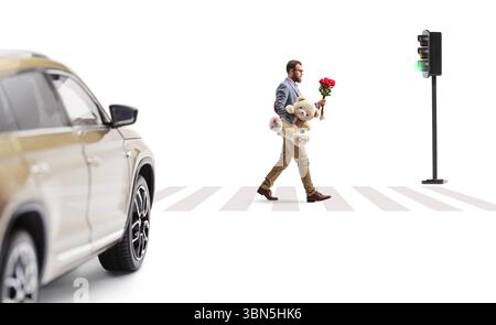 Man with a bunch of red roses and a teddy bear crossing a street isolated on white background Stock Photo