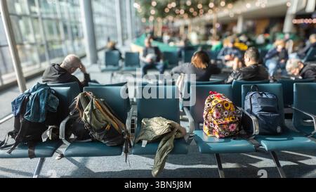 Five carry-on suitcases neatly placed on five seats in an airport departure lounge. Stock Photo