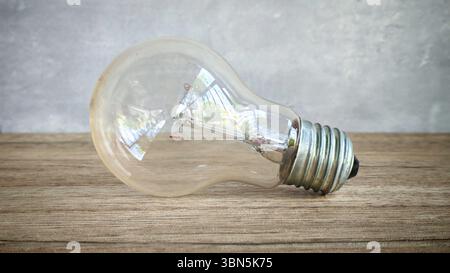 Classic Incandescent Light Bulb on Wooden Table, Symbolizing Ideas, Innovation, and Energy Stock Photo