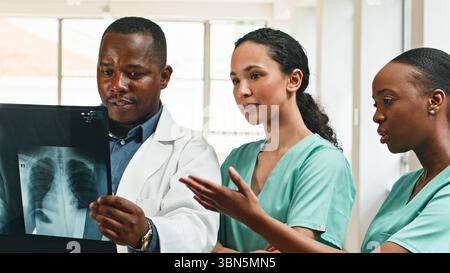 Diverse Medical Professionals Collaborating on X-Ray Analysis in Modern Healthcare Facility Stock Photo