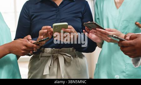 Group of Healthcare Professionals Collaborating Using Smartphones in a Workplace Setting Stock Photo