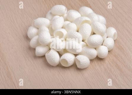 Pile of open natural silk cocoons on wooden table Stock Photo