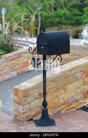 standing black metal mailbox on brick footpath. Stock Photo