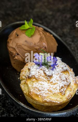 A rosemary and a chocolate-mint flavoured muffin on a black plate. Stock Photo