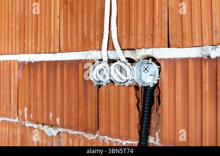 Socket back boxes with wires in a brick wall. New electrical wiring installation Stock Photo