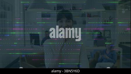 Smiling woman in office with colorful digital glitch image overlay Stock Photo