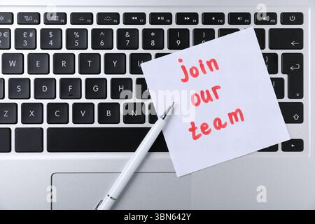 Paper note with words Join Our Team and pen on laptop, top view Stock Photo