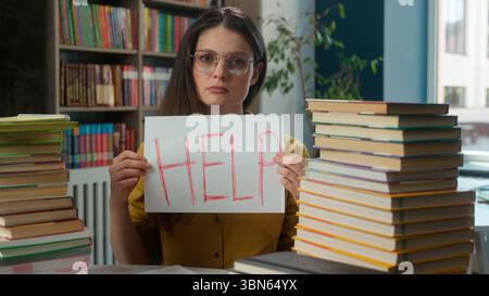 Sad worried tired exhausted girl Caucasian woman high school student teacher helpless stressful books studying learning college university library Stock Photo