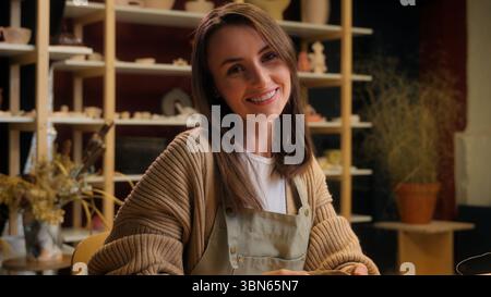 Smiling girl Caucasian woman artist sculptor craftswoman potter designer art work in studio small business owner decorator in pottery workshop clay Stock Photo