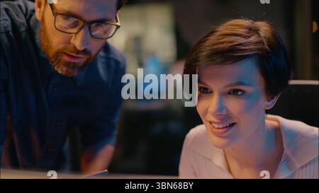 Caucasian business man consult woman businesswoman businessman smiling co-workers girl guy looking at computer screen internet trading commerce at Stock Photo