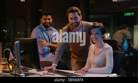 Business colleagues businessmen businesswoman men woman multiracial co-workers talking friendly conversation night evening office work overtime Stock Photo