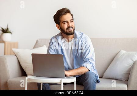 Portrait Of Pensive Arab Freelancer Guy Working With Laptop Computer At Home Stock Photo