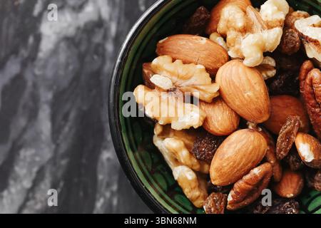 Mixed nuts in ceramic bowl. Healthy snack with almonds, walnuts and hazelnuts on dark marble background. Natural protein-rich food. Closeup view. Stock Photo
