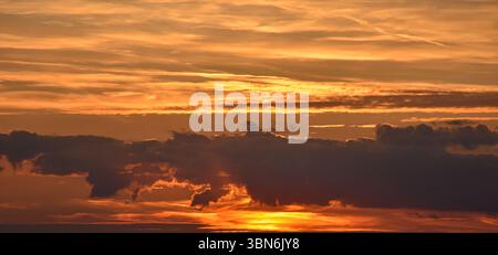Magical sunset sky with warm glowing clouds and subtle transitions of color from gold and orange to soft blue-gray Stock Photo