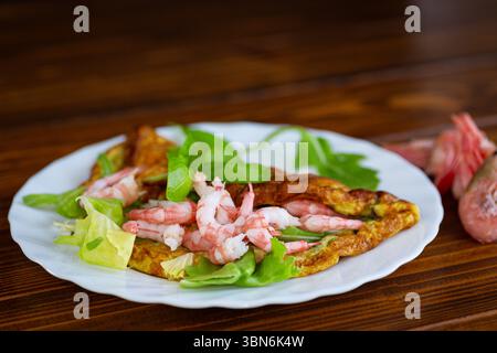 Omelette with seafood and greens on a white plate. Stock Photo