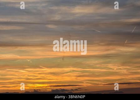 Sunset scene with pastel-colored sky, glowing clouds, and natural gradients from deep orange to calm gray-blue background Stock Photo