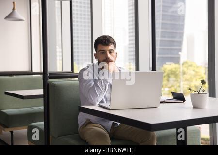 Young man sitting at table consider information on notebook screen Stock Photo