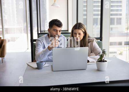 Multiethnic colleagues mature woman young man thinking by notebook screen Stock Photo