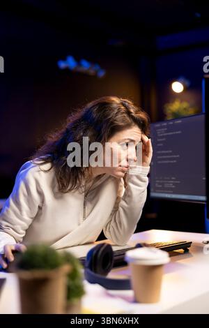 Tired software developer hurting from too much stress accumulated while doing quality assurance. Computer scientist suffers from headache after inspecting coding on PC for too long Stock Photo