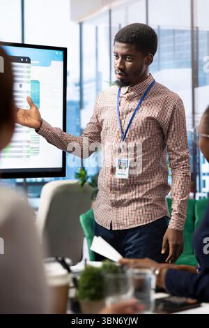 Diverse work team discussing digital marketing trends on interactive board, using analytics to improve sales numbers in a meeting. Business experts developing a startup company. Stock Photo