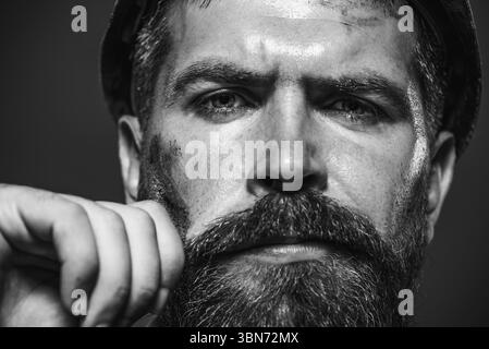 Closeup portrait serious architect, foreman or builder in hard hat. Handsome male engineer or construction worker in safety helmet. Bearded builder ma Stock Photo