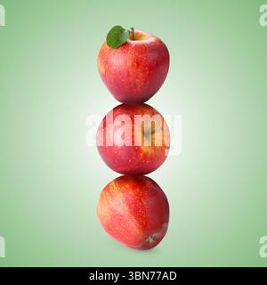 Red apples stacked on top of each other against pastel green background. Balance Stock Photo