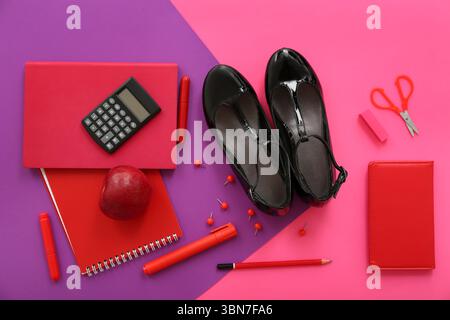 Cute school shoes with fresh apple, calculator and different stationery on color background Stock Photo