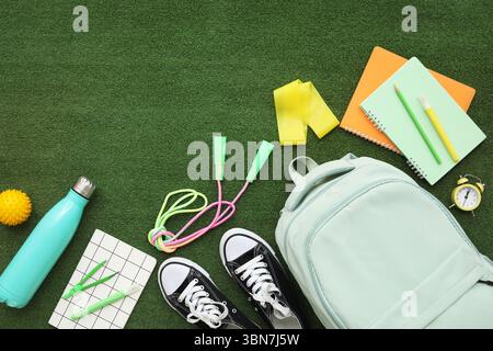 Composition with backpack, school supplies and sports equipment on green grass background Stock Photo