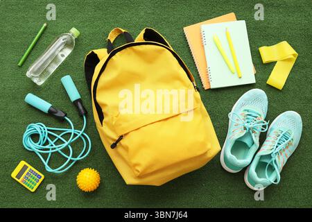 Composition with backpack, school supplies and sports equipment on green grass background Stock Photo