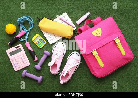Composition with backpack, school supplies and sports equipment on green grass background Stock Photo