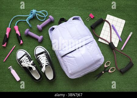 Composition with backpack, school supplies and sports equipment on green grass background Stock Photo