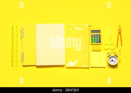 Composition with alarm clock, calculator and different school stationery on yellow background Stock Photo