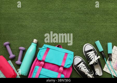 Composition with backpack, school supplies and sports equipment on green grass background Stock Photo