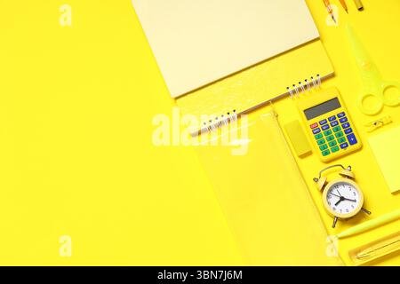Composition with alarm clock, calculator and different school stationery on yellow background Stock Photo