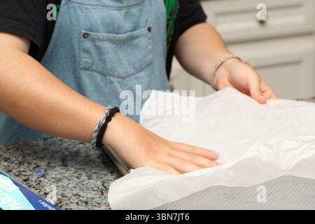 A baker prepares a sheet of parchment paper before baking. Stock Photo