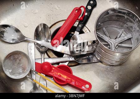 Baking utensils and measuring cups, spoons in kitchen sink. Stock Photo