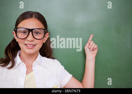 Flat design illustration is showing girl wearing glasses pointing at green chalkboard, copy space Stock Photo