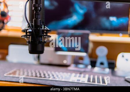 Stylish computer desk setup with dual monitors, a microphone, DAC/AMP stack, white speakers, and warm lighting. Cozy and modern workspace with wooden. Stock Photo