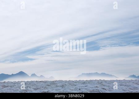 Flat design salt flat is stretching toward misty mountain ridge under wispy cloud layers Stock Photo
