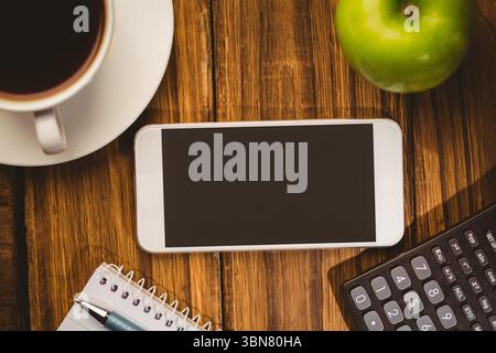 Smartphone is sitting on flat design desk with coffee cup, saucer, apple, notebook, pen, calculator Stock Photo